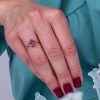 Edinstven_zarocni_prstan_z_zelenim_safirjem_in_rubini_na_roki One_of_a_kind_green_sapphire_and_ruby_halo_engagement_ring_on_hand