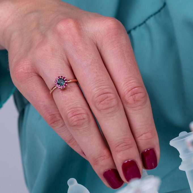 Edinstven_zarocni_prstan_z_zelenim_safirjem_in_rubini_na_roki One_of_a_kind_green_sapphire_and_ruby_halo_engagement_ring_on_hand
